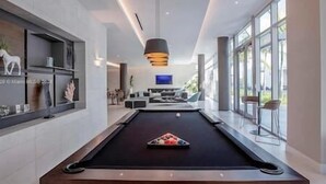 A modern pool table with a black felt surface and a triangular arrangement of billiard balls. - Luxury Penthouse with Water Views and  Massive Private Terrace and Free Parking (Miami)