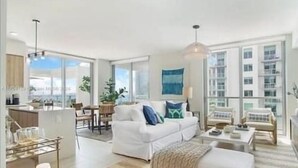 A modern living room with a white sofa, a coffee table, and a dining area with chairs and a table. - Luxury Penthouse with Water Views and  Massive Private Terrace and Free Parking (Miami)