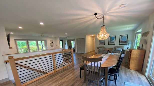 A spacious living area with a wooden staircase, a dining table, and a chandelier.