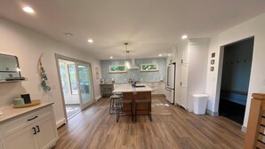 A modern kitchen with a central island, white cabinets, and a large window.