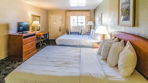 A hotel room with two beds, a desk with a chair, a television, and a window with curtains. - Montrose Valley Lodge (Montrose)