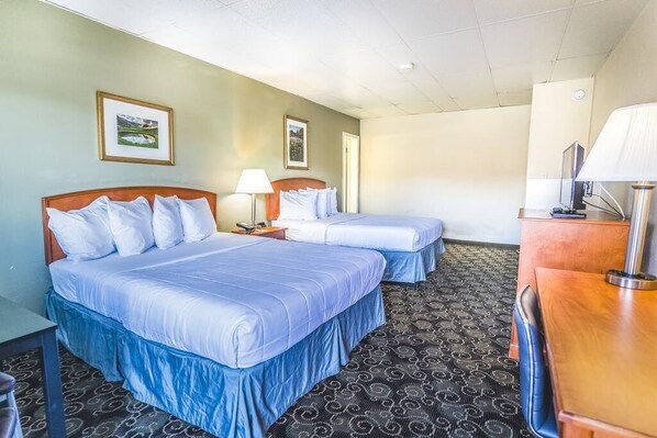 A hotel room with two beds, a desk, and a TV. - Montrose Valley Lodge (Montrose)