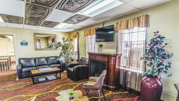 A hotel lobby with a leather sofa, armchairs, a fireplace, and a large plant. - Montrose Valley Lodge (Montrose)