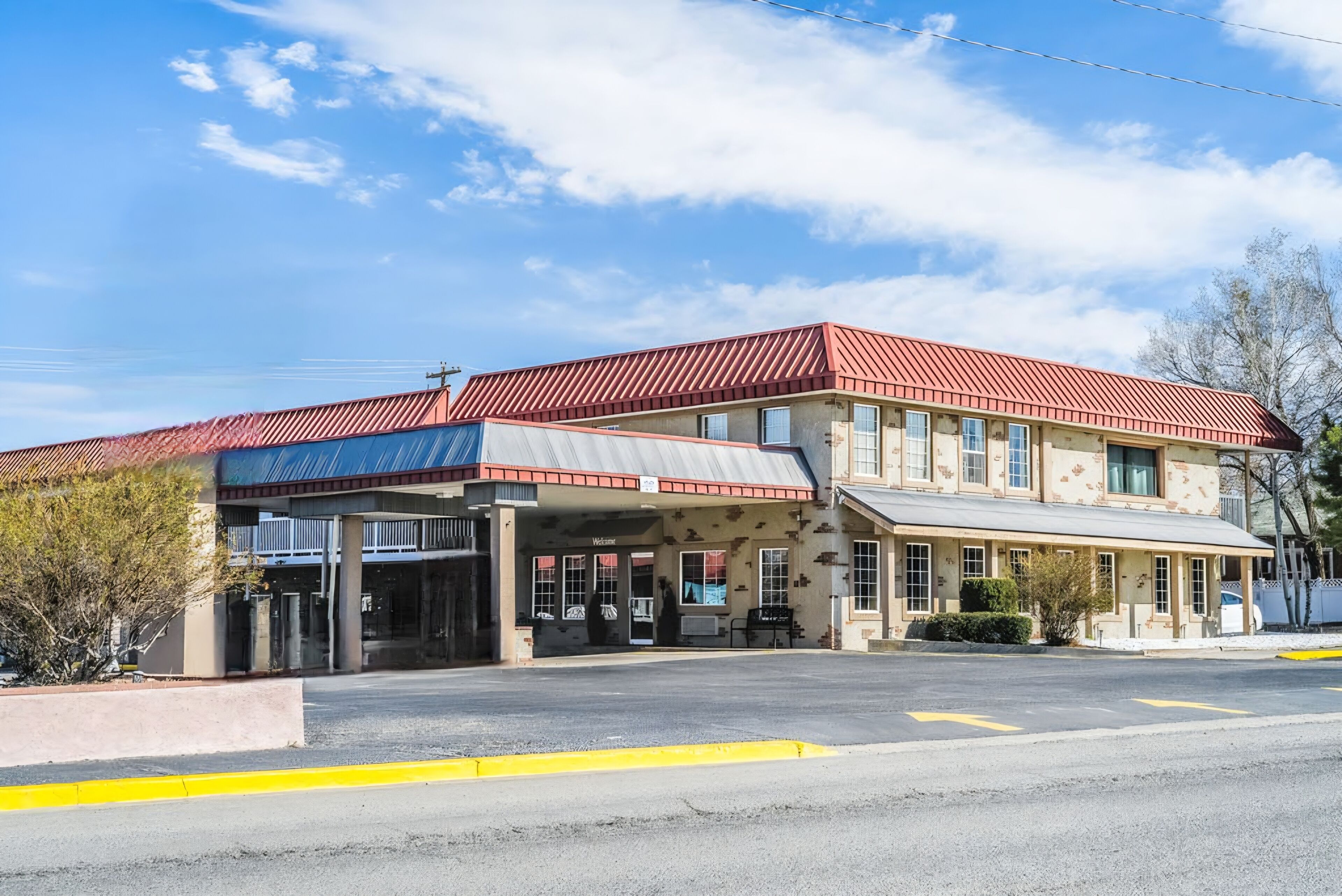 A two-story motel with a red roof and beige exterior.