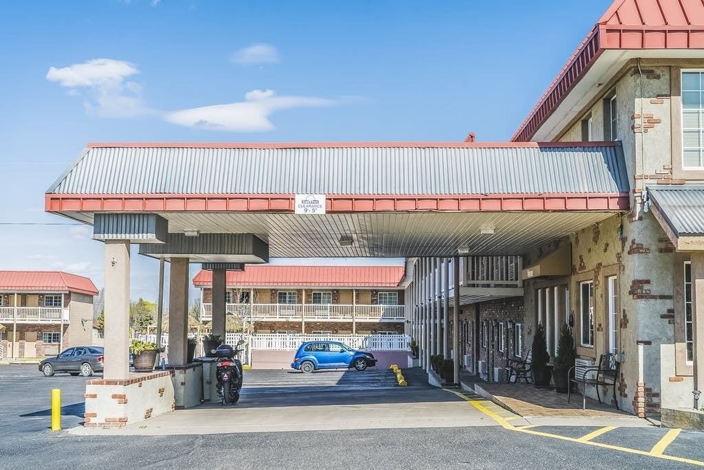 Een tankstation met een rood dak en een wit bord waarop staat dat het een Chevron-station is. Er staan auto's en een motorfiets geparkeerd voor.