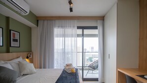 A modern hotel room with a bed, a desk, and a balcony with a city view. - Cozy Refuge Near Allianz Parque Sp-p1504a (São Paulo)