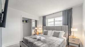 A modern bedroom with a large bed, bedside lamps, a wardrobe, and a television.
