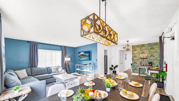 A modern living room with a dining area, featuring a sofa, dining table, and a coffee bar.