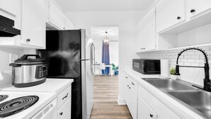 A modern kitchen with white cabinetry, a black refrigerator, a microwave, and a sink.