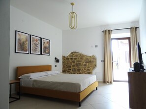 A bedroom with a bed, a stone accent wall, a ceiling light, and a window with curtains.