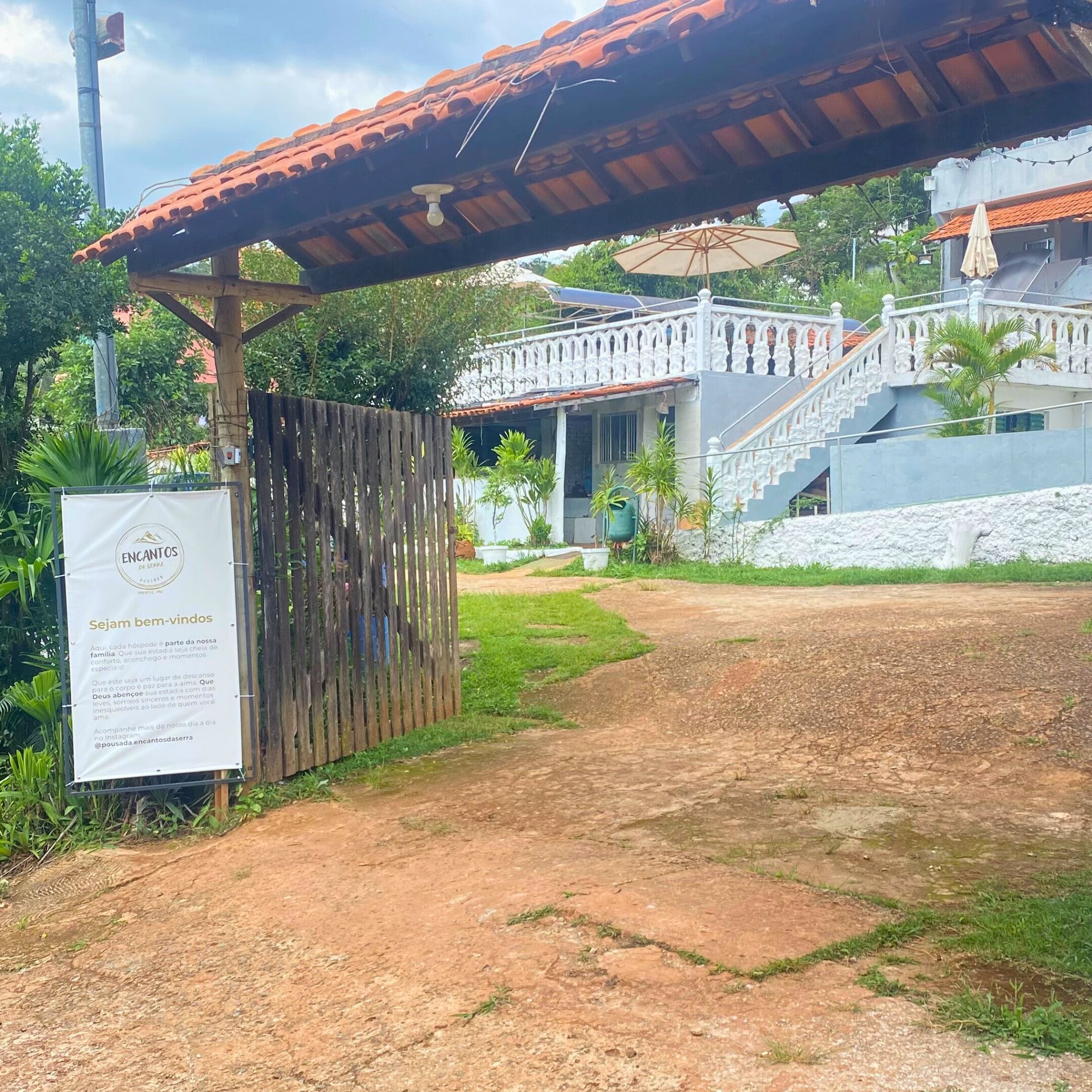 A pathway leading to a building with a tiled roof and a white fence.