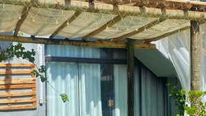 A covered outdoor area with a wooden pergola, a sliding glass door, and a green artificial turf. - Pousada Encantos da Serra Macacos (Nova Lima)