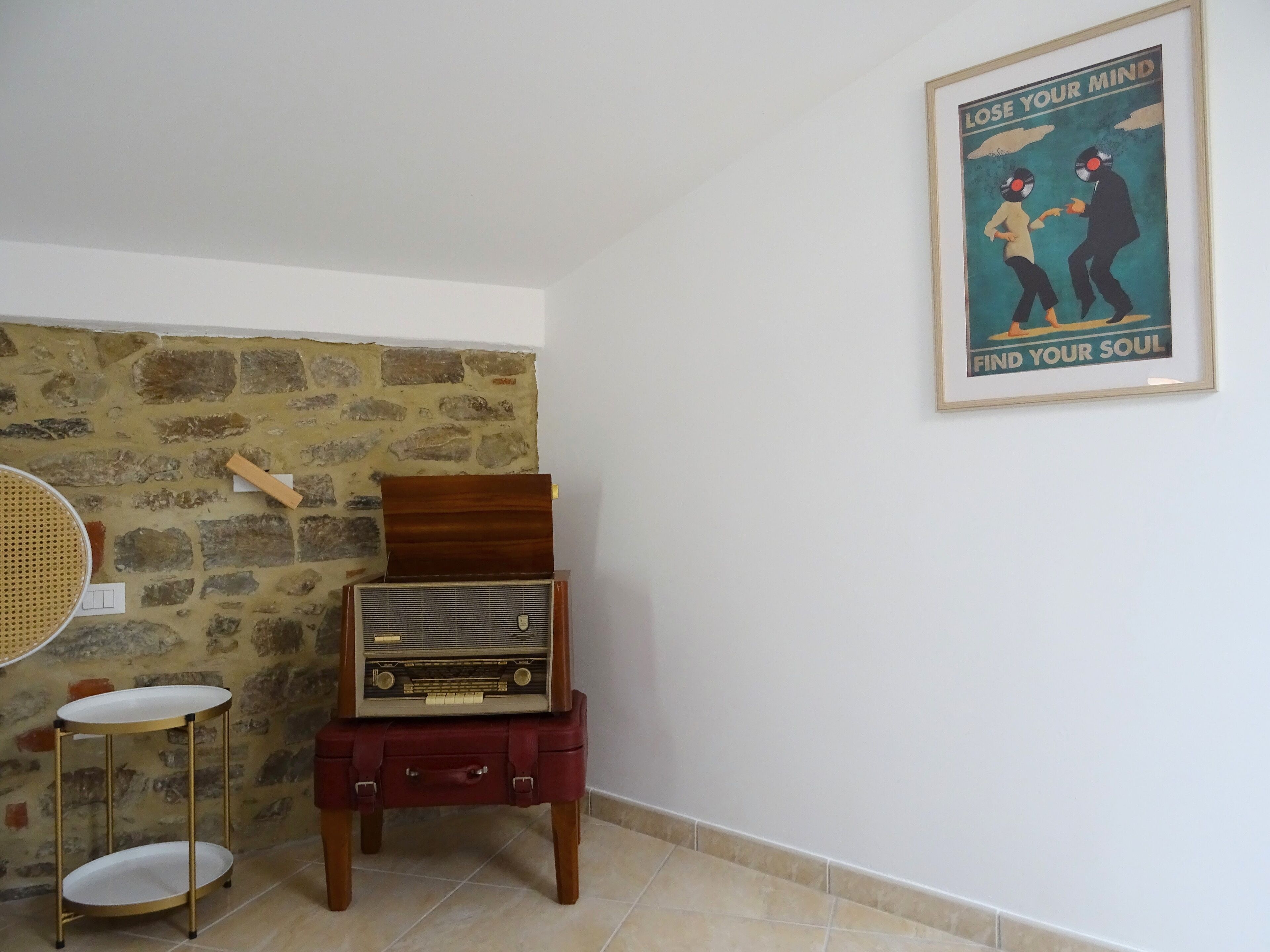 Ein altes Radio auf einem Holzständer, an der Wand ein Poster.