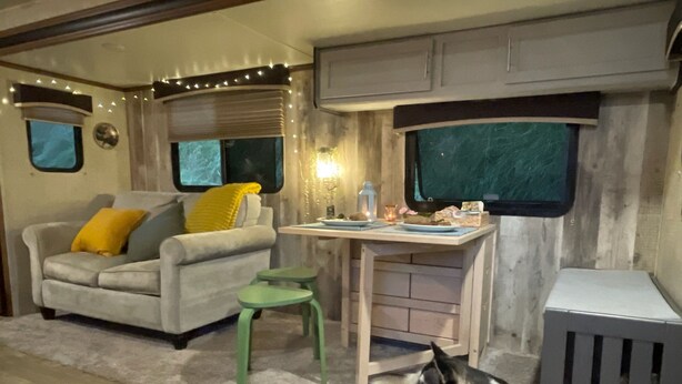 A cozy RV interior with a sofa, a small table, and a dog resting on the floor.