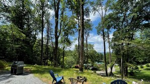 A campsite with a gravel path, blue chairs, a table, and a grill.