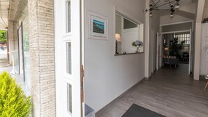 A hallway with a wooden floor, a mirror, a framed picture, and a door leading to another room. - Hotel Ros Mary (Ribadeo)