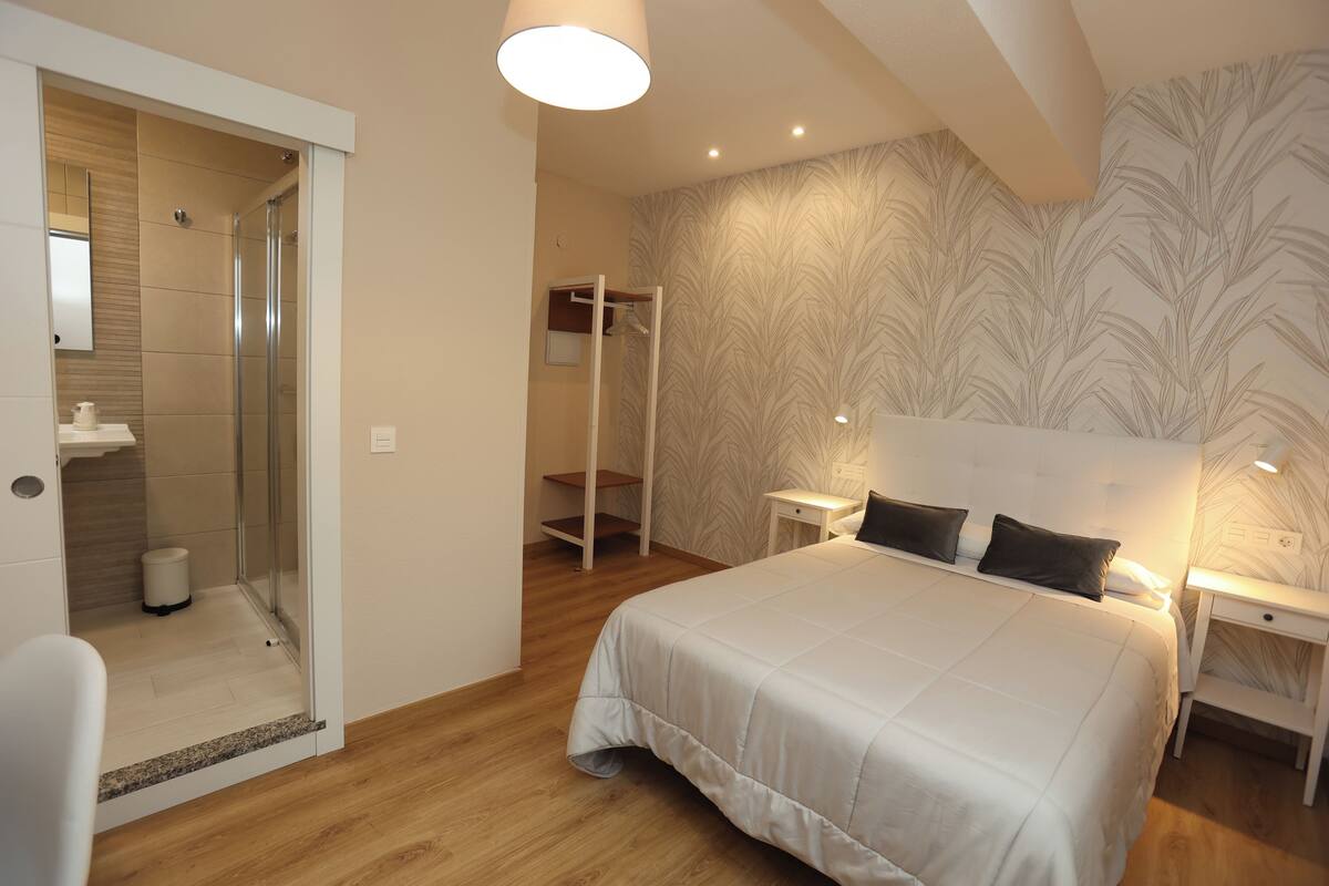 Ein Schlafzimmer mit einem großen Bett, einem begehbaren Kleiderschrank und einem Duschbereich.