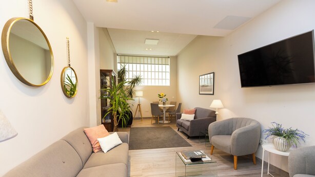 A modern living room with a sofa, armchairs, a coffee table, and a TV. - Hotel Ros Mary (Ribadeo)
