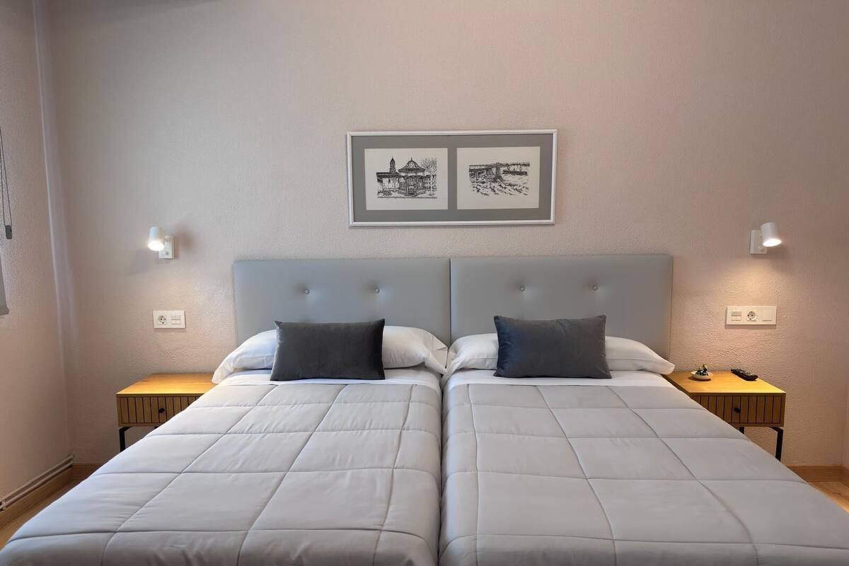 Ein Doppelbett mit grauem Kopfteil, zwei Nachttische und ein gerahmtes Bild darüber.