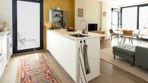 A modern kitchen with a central island, a dining area with a table and chairs, and a cozy seating area with a sofa. - Cozy furnished apartment on resort with unique swimming lake (19200)