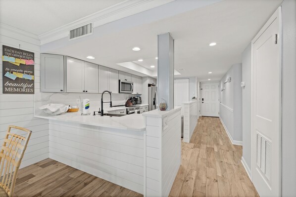 Una cocina moderna con armarios blancos, una isla central y piso de madera.
