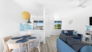 A modern living space with a dining area, a sofa, and a kitchen.