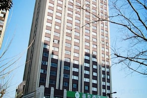 A tall building with multiple floors and a green sign at the base.