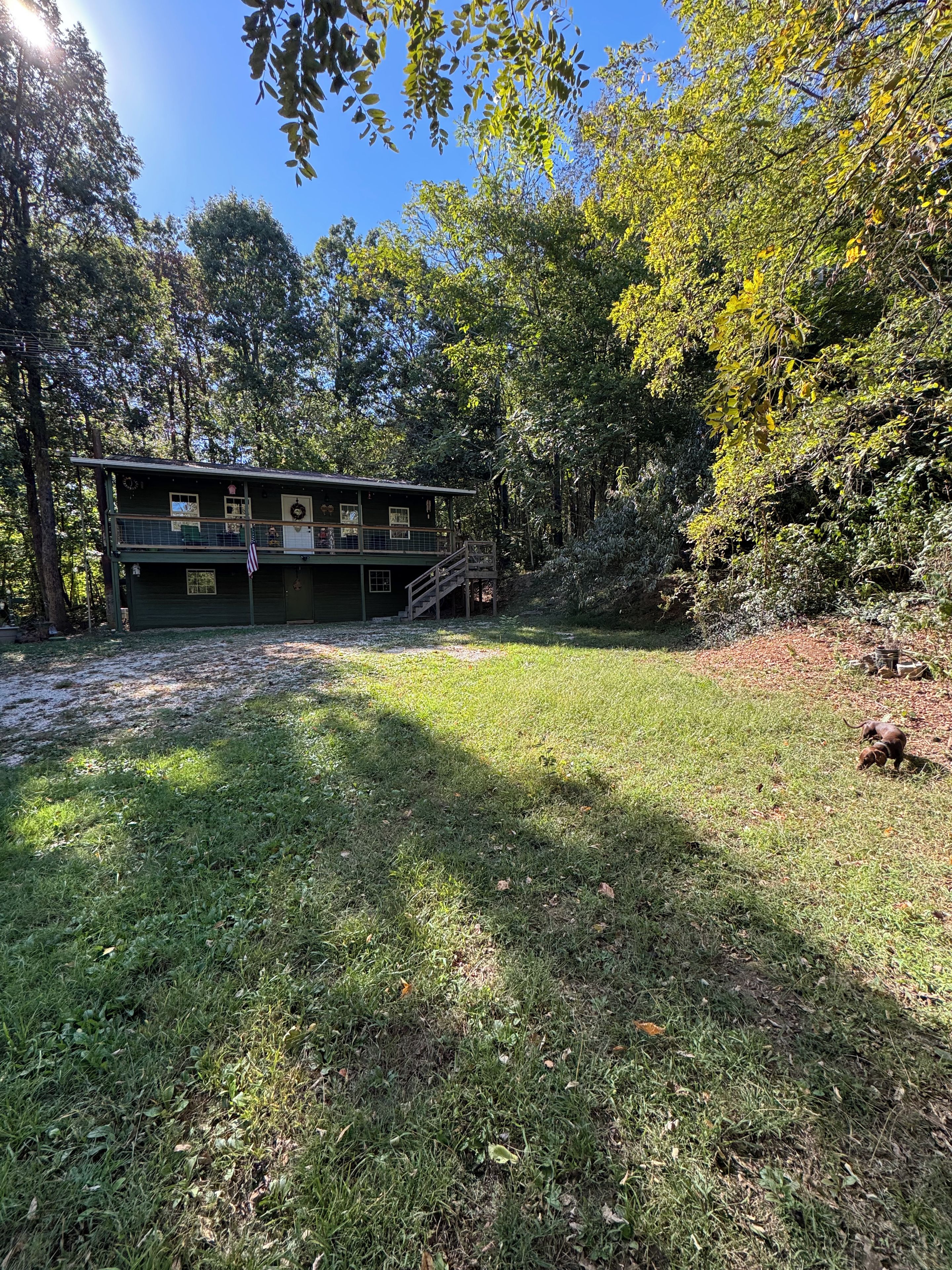 A two-story building with a balcony, surrounded by trees and a grassy yard.
