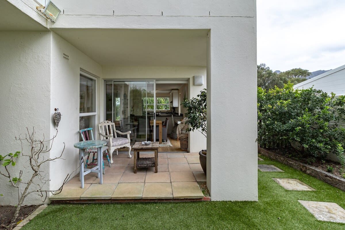 A covered patio with a seating area, a small table, and a potted plant.