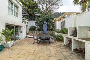 A patio with a table and chairs, surrounded by a white wall and a wooden fence.