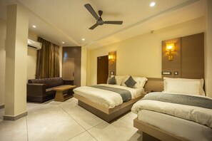 A hotel room with two beds, a sofa, a ceiling fan, and wall-mounted lights. - Hotel Shankar Palace Beawar (Beawar)