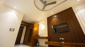 A modern bathroom with a ceiling fan, wooden paneling, a mounted TV, and a vanity with a mirror. - Hotel Shankar Palace Beawar (Beawar)