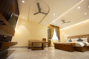 Una habitación de hotel moderna con una cama grande, un sofá, un escritorio y dos ventiladores de techo.
