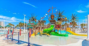 A water park with a green water slide, a pool area, and palm trees. - Beckham by The Sea (Myrtle Beach)