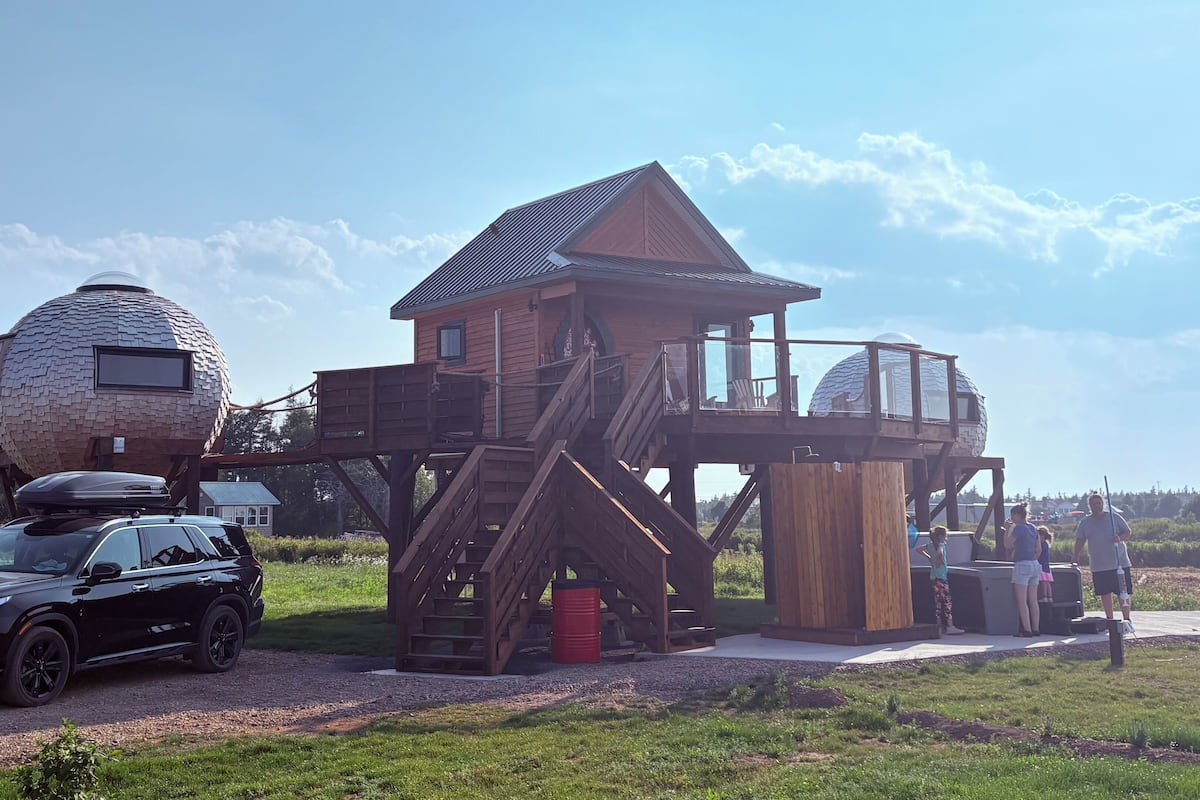 Ein hölzernes Haus mit einer kuppelförmigen Struktur und einer Treppe, die zu einem Deck führt.