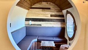 Una habitación circular con techo de madera, un banco, una mesa y un espejo.