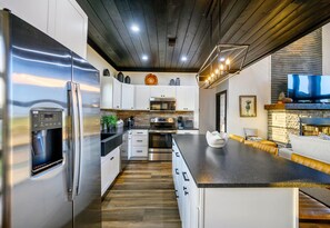 A modern kitchen with stainless steel appliances, white cabinetry, and a wooden ceiling. - Heated & Chilled Pool | Pickleball | Kid's Playset (Broken Bow)