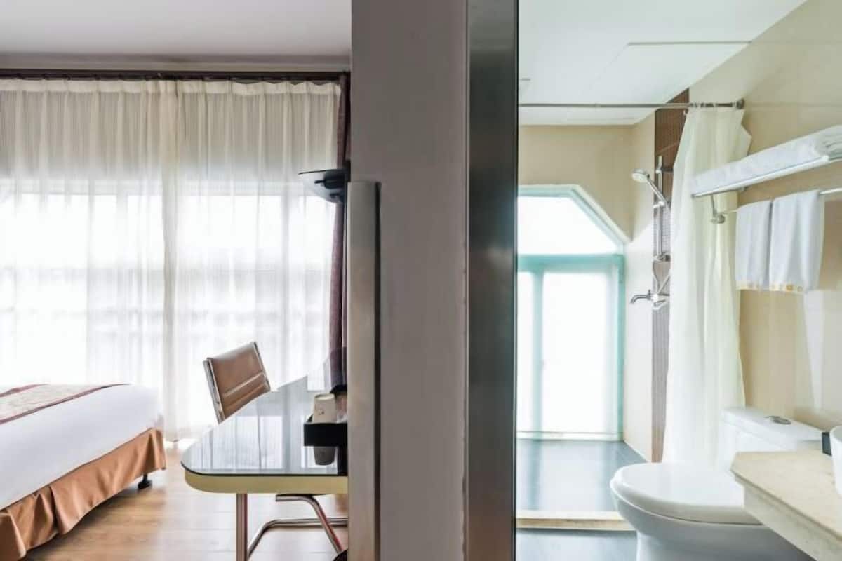 Ein Hotelzimmer mit einem Bett, einem Esstisch und einem Badezimmer mit Toilette und Dusche.