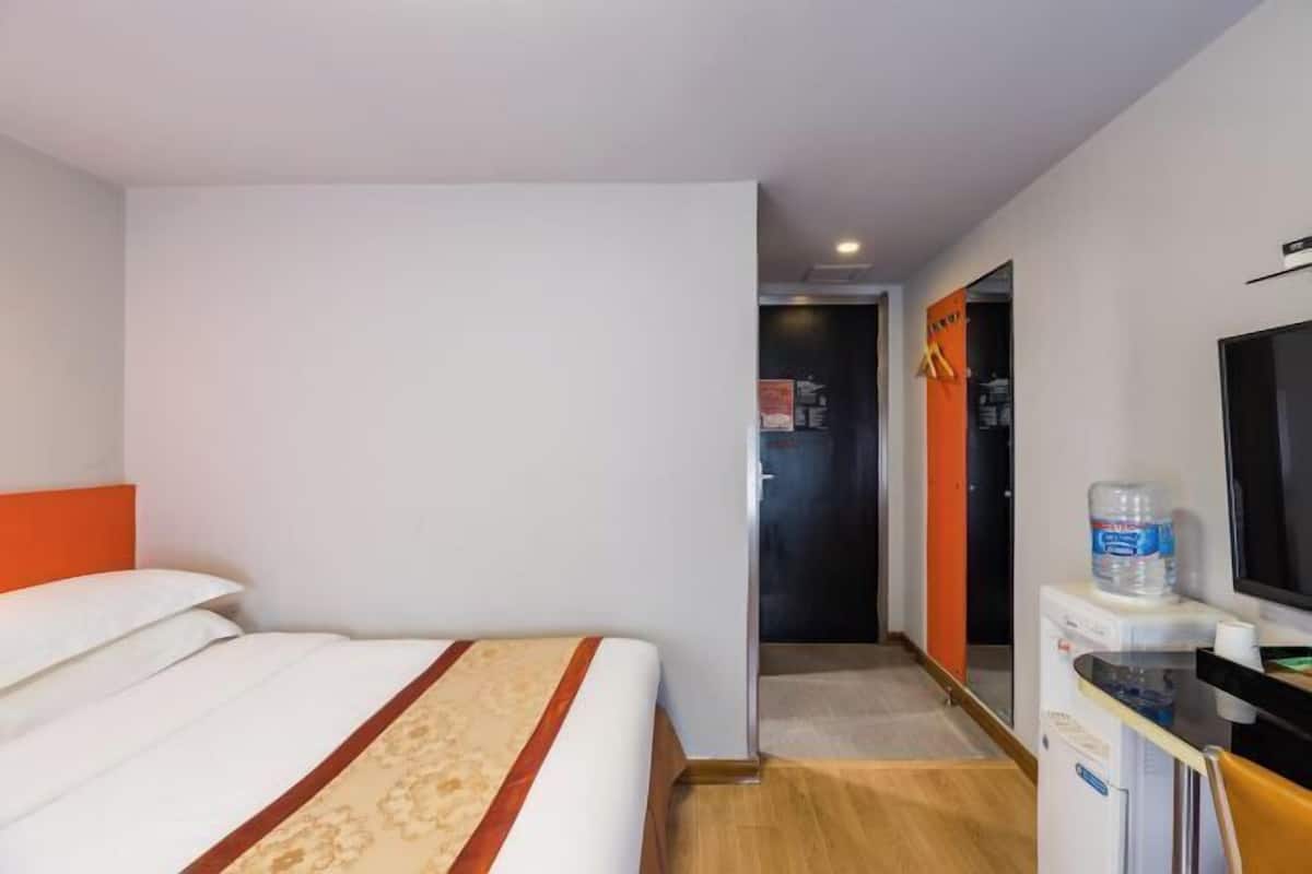 Ein Hotelzimmer mit einem Bett, einem Fernseher, einem Wasserspender und einer Tür zu einem anderen Raum.