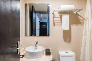 A bathroom with a round sink, a toilet, a towel rack, and a mirror.