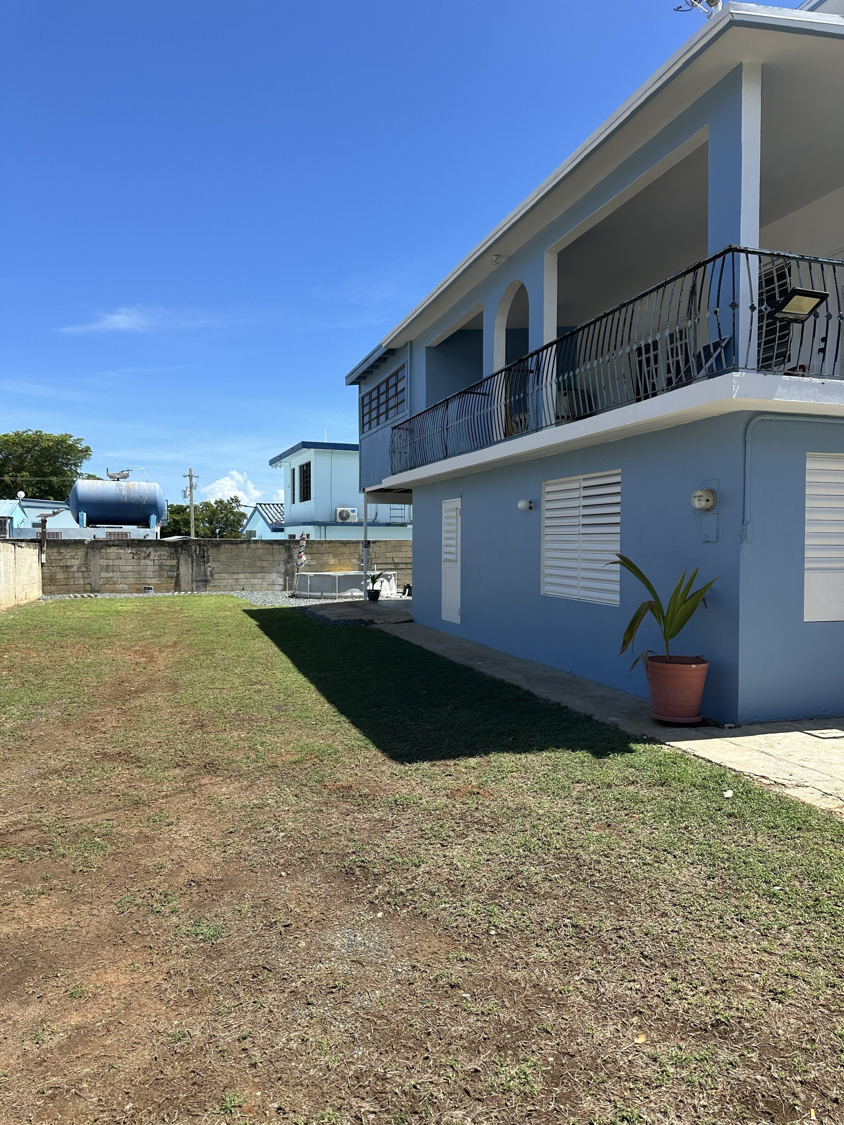 Un immeuble d’habitation doté d’un balcon, d’une plante en pot et surplombant un ciel bleu dégagé.
