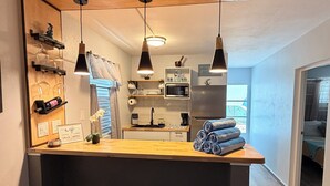 Una cocina compacta con encimera de madera, luces colgantes y un fregadero, además de un microondas.