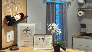 Zona de recepción de un hotel con un mostrador de madera, copas de vino, una botella de vino, un cartel que indica 'Delfin's Villa #1' y un letrero de 'wifi'.