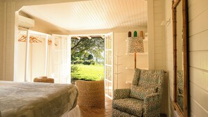 Ein Schlafzimmer mit einem Bett, einem Sessel, einer Lampe und einem großen Spiegel.