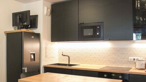 Una cocina compacta equipada con microondas, un lavamanos y una cafetera.