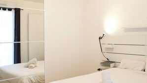 Una habitación de hotel con dos camas, una mesita de noche, una lámpara y una ventana con cortinas.