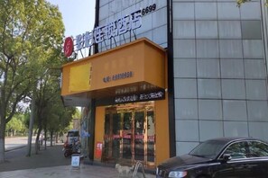 A building with a storefront featuring a sign with Chinese characters and a phone number. - Junyi Hotel (Shanghai Chongming District Xue Gong Road ) (Shanghai)