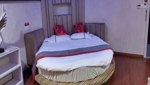A bed with a headboard, a bedside table, and a wall-mounted shelf. - Junyi Hotel (Shanghai Chongming District Xue Gong Road ) (Shanghai)