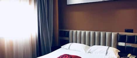 Una habitación de hotel con una cama, un cabecero, una mesita de noche con un teléfono y una obra de arte colgada en la pared.