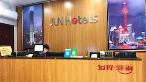 A reception desk at JUNHotels with a cityscape backdrop, a computer, and informational brochures. - Junyi Hotel (Shanghai Chongming District Xue Gong Road ) (Shanghai)